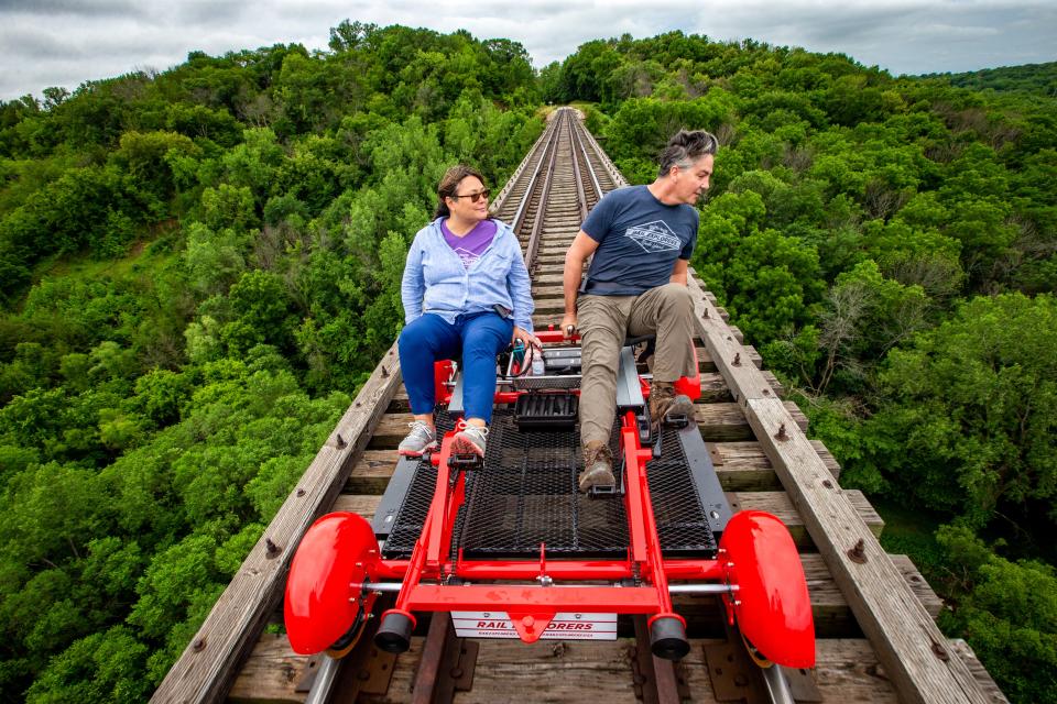 Mary Joy Lu, CEO of Rail Explorers and her husband Alex Catchpoole, Rail Explorers COO, ride over the 156-foot-tall Bass Point Creek High Bridge outside of Boone.