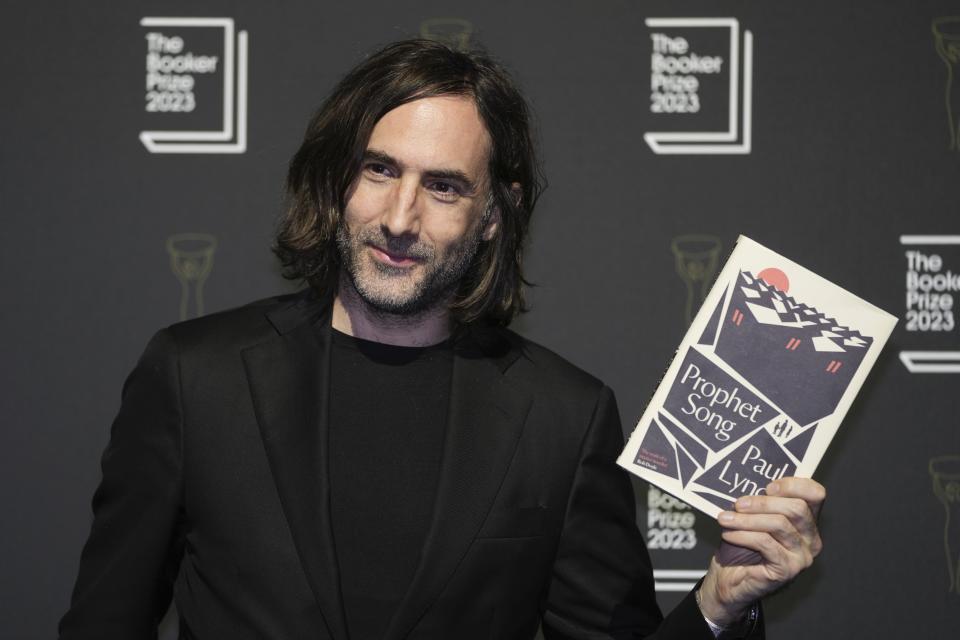 Irish author Paul Lynch poses with his book "Prophet Song" during a photocall with the six shortlisted authors for the Booker Prize 2023, in London, Thursday, Nov. 23, 2023 ahead of the award ceremony on Nov. 26 in London. (AP Photo/Kin Cheung)