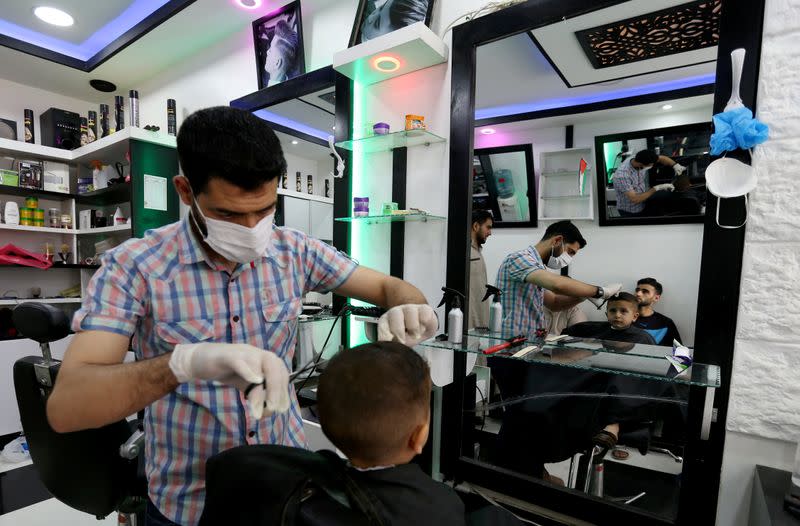 A barber cuts the hair of a boy as Palestinians prepare for the upcoming holiday of Eid al-Fitr marking the end of Ramadan, amid concerns about the spread of the coronavirus disease
