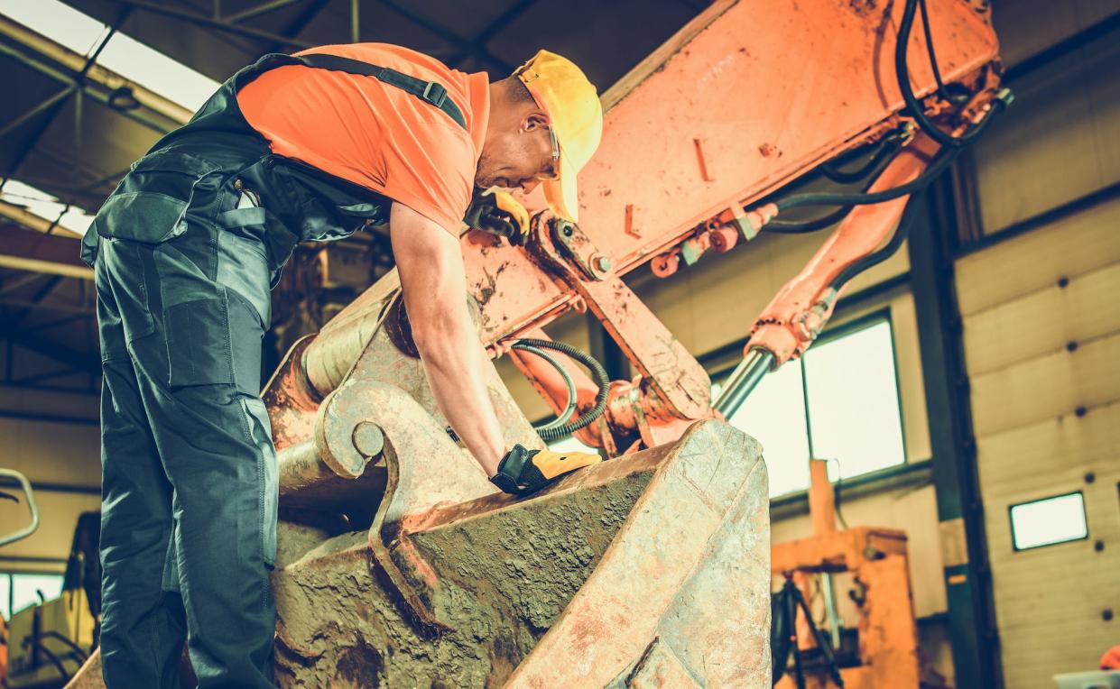 A construction worker standing on a bulldozer