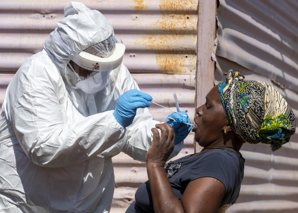 A woman opens her mouth for the heath worker to collect a sample for coronavirus testing during the screening and testing campaign aimed to combat the spread of COVID-19 at Lenasia South, south Johannesburg, South Africa, Tuesday, April 21, 2020. (AP Photo/Themba Hadebe)