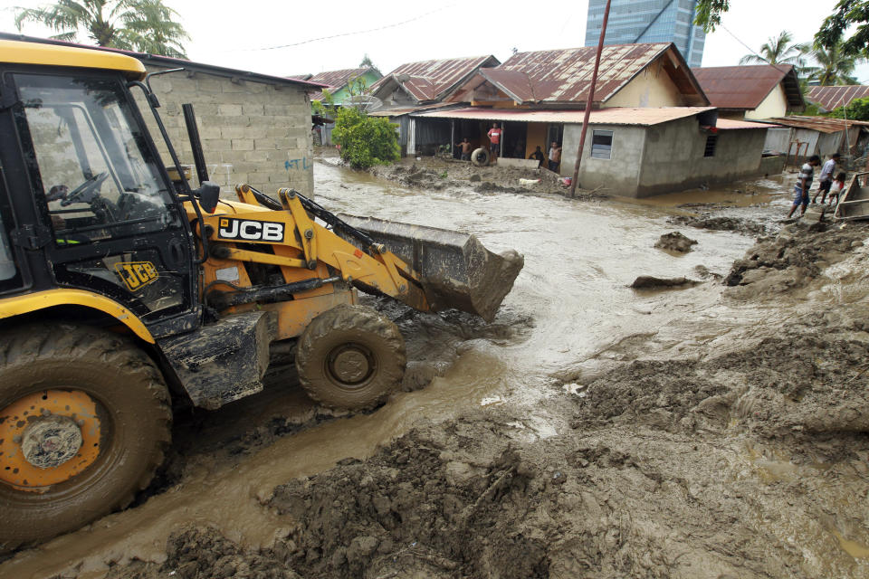 A heavy machinery clears up mud from a neighborhood following a flood in Dili, East Timor, Monday, April 5, 2021. Multiple disasters caused by torrential rains in eastern Indonesia and neighboring East Timor have left a number of people dead or missing as rescuers were hampered by damaged bridges and roads and a lack of heavy equipment Monday. (AP Photo/Kandhi Barnez)