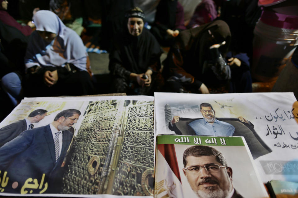 Posters of Egypt's ousted President Mohammed Morsi with Arabic that reads: "No god but Allah", center, and "Coming Back" are displayed for sale outside Rabaah al-Adawiya mosque, where supporters of Egypt's ousted President Mohammed Morsi have installed a camp and hold daily rallies at Nasr City, in Cairo, Egypt, Thursday, Aug. 1, 2013. (AP Photo/Hassan Ammar)