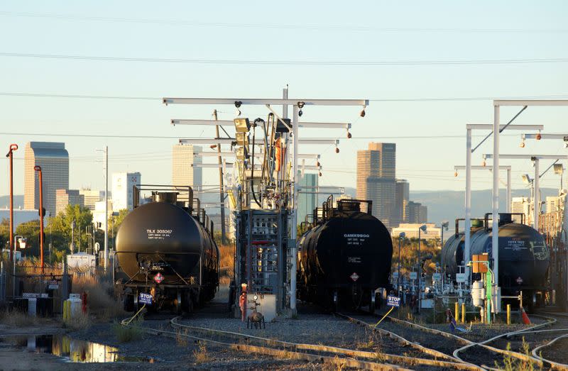 FILE PHOTO: Oil tanker railcars are parked at a filling rack at sunrise with the Denver downtown skyline in the background