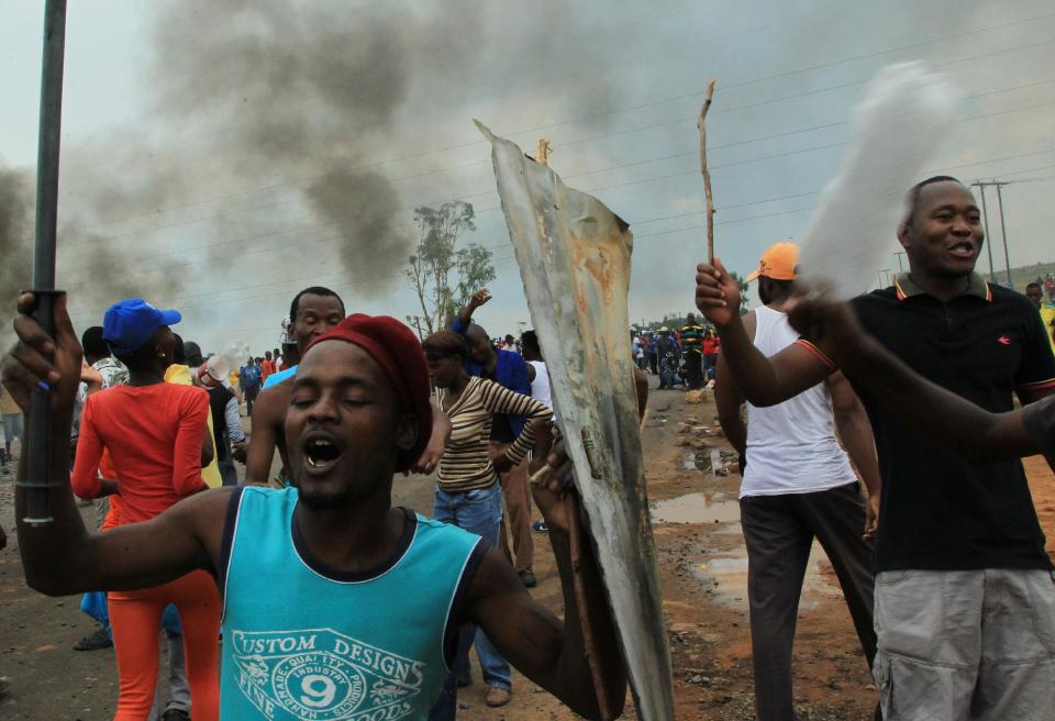 Residents sing during their protest at Zithobile in Bronkhorstspruit, near Pretoria, South Africa, Thursday, Feb. 6, 2014. Demonstrators set several buildings, including a clinic, on fire on Wednesday in the Bronkhorstspruit district, east of the capital, Pretoria, to protest what they say are high electricity prices. (AP Photo/Themba Hadebe)