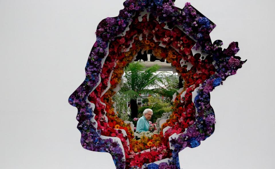 Queen Elizabeth II pictured through a gap in a floral exhibit by the New Covent Garden Flower Market, which features an image of the Queen, during a visit to the 2016 Chelsea Flower Show (AFP/Getty)