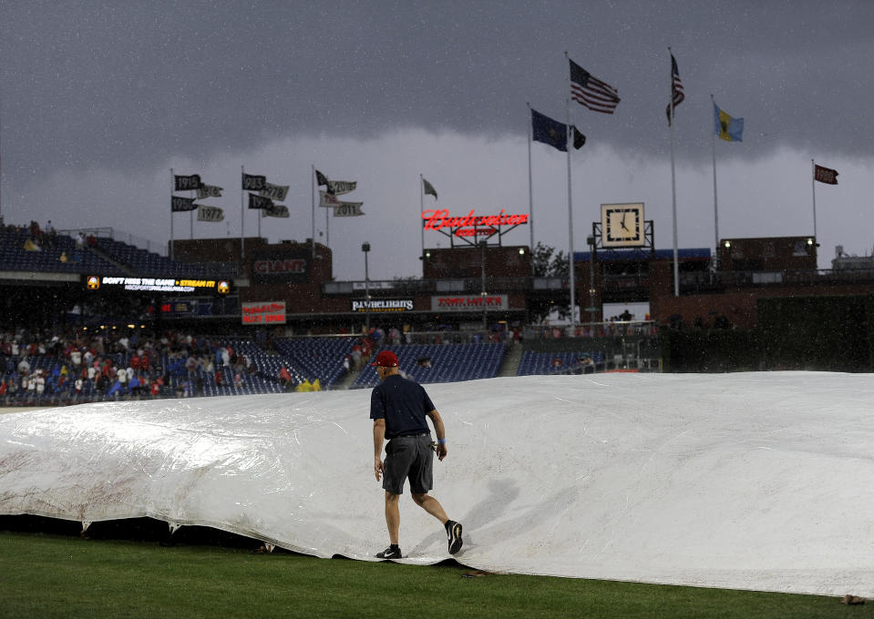 Grounds crew members cover the field during a rain delay in the fourth inning of a baseball game between the Philadelphia Phillies and the New York Mets, Saturday, Aug. 18, 2018, in Philadelphia. (AP Photo/Michael Perez)