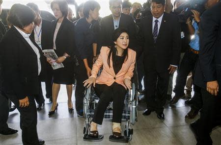 Thailand's Prime Minister Yingluck Shinawatra (C) arrives on a wheelchair at the Royal Police Cadet Academy in Nakorn Pathom province, March 18, 2014. REUTERS/Athit Perawongmetha