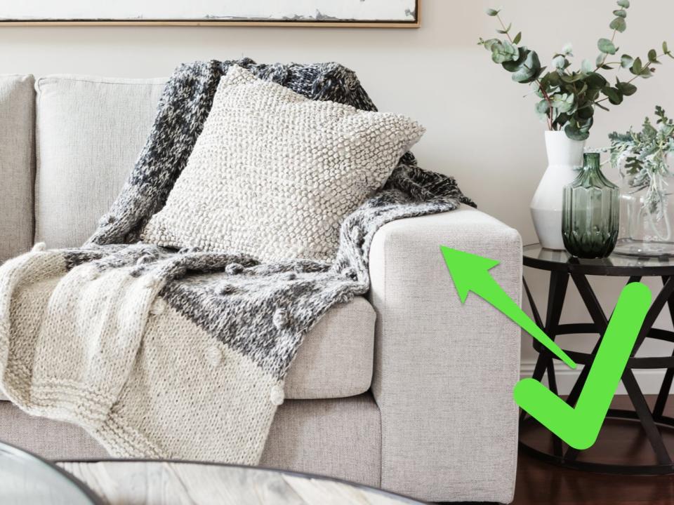 Living room with a white couch with a durable fabric and a green arrow and checkmark pointing to couch