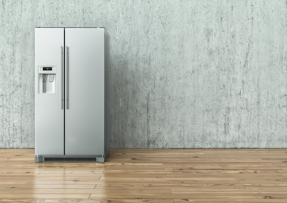 Modern Stainless Steel Refrigerator on a concrete wall and on a wooden floor -- 3D Rendering
