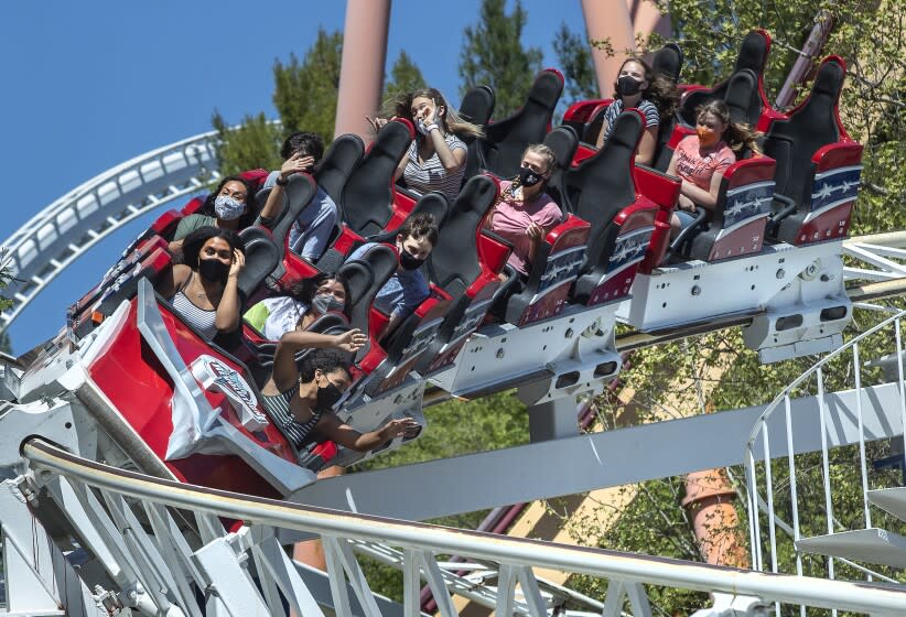 VALENCIA, CA - APRIL 02, 2021: People ride the Revolution roller coaster, the world's first looping roller coaster, at Six Flags Magic Mountain in Valencia on the second day that the park re-opened after more than a year of being closed due to the coronavirus outbreak. In order to maintain social distancing, every other row was kept empty. The only exception was for members of the same family who were allowed to sit in two rows right next to each other. (Mel Melcon / Los Angeles Times)