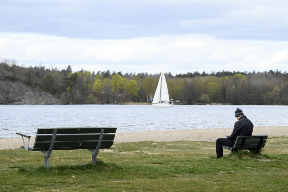 A man sits alone on a bench on the beach of lake Malaren, during the coronavirus outbreak in Satra south east of Stockholm, Saturday, April 25, 2020. (Henrik Montgomery/TT News Agency via AP)