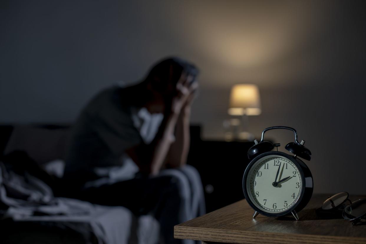 Depressed senior Asian man sitting in bed cannot sleep from insomnia