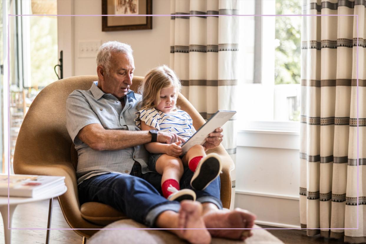  A grandfather with his granddaughter sat on his lap and reading a book. 