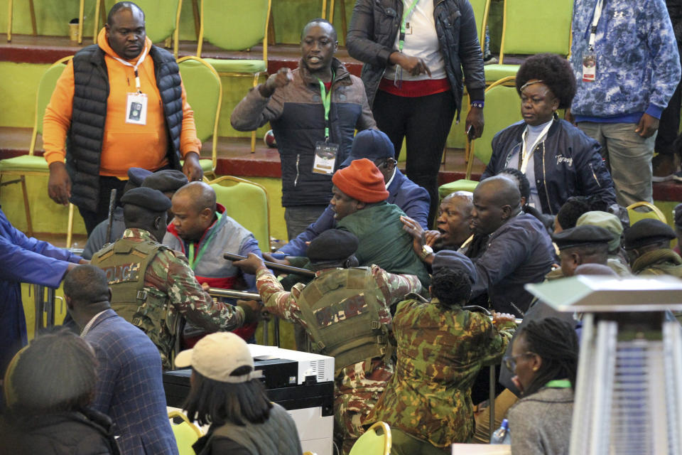 Scuffles break out between political party agents and police, including presidential candidate Raila Odinga's chief agent Saitabao Ole Kanchory, center left in grey and red jacket, at the electoral commission's national tallying center in Nairobi, Kenya late night Saturday, Aug. 13, 2022. Kenya's peaceful presidential election saw a brief disruption late Saturday when police responded to scuffles at the national tallying center amid tensions over the close results. (AP Photo)