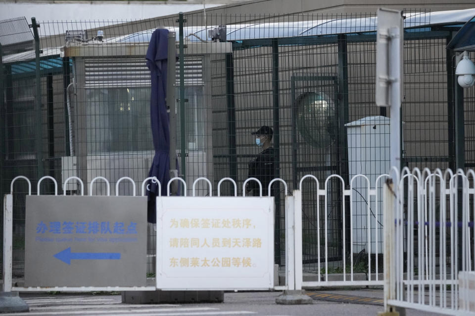 A security guard stands guard behind fences around the U.S. embassy near a sign board directing visa applicants in Beijing on Sept. 6, 2021. The Chinese government says at least Chinese 500 students have been rejected under a policy issued last year by then U.S. President Donald Trump that is aimed at blocking Beijing from obtaining U.S. technology with possible military uses. (AP Photo/Ng Han Guan)