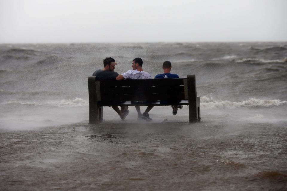 Tres hombres aparecen sentados en un banco cercano al lago Pontchatrain horas antes de la llegada del huracán Isaac a las costas de Nueva Orleans. (Photo by Chris Graythen/Getty Images)