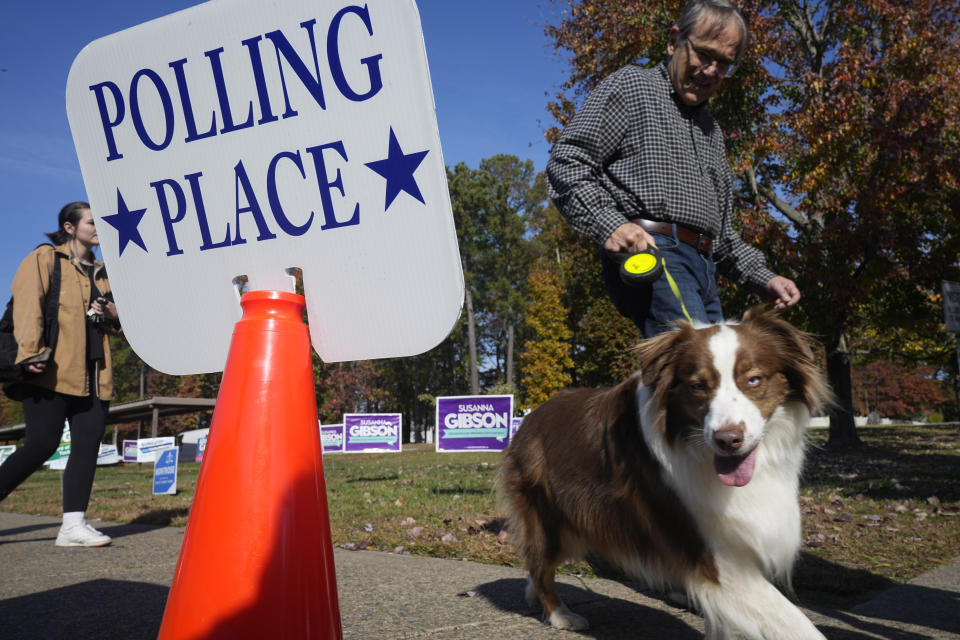 A voter leads his dog past a polling sign after voting at a polling station Tuesday Nov. 7, 2023, in Richmond, Va. (AP Photo/Steve Helber)