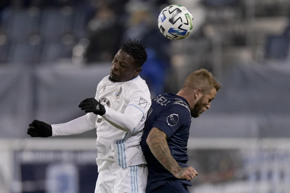 Minnesota United defender Bakaye Dibassy, left, and Sporting Kansas City forward Johnny Russell battle for the ball during the second half of an MLS soccer match Thursday, Dec. 3, 2020, Kansas City, Kan. Minnesota won 3-0. (AP Photo/Charlie Riedel)