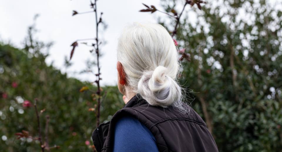 woman with white hair wearing black vest outside in nature