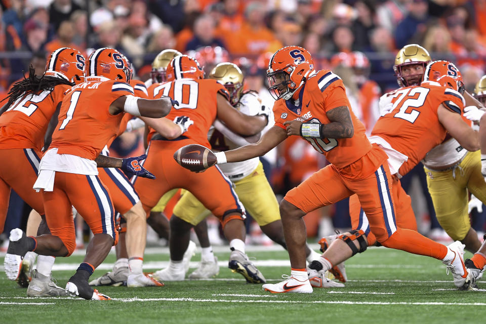 Syracuse quarterback Carlos Del Rio-Wilson, right, hands the ball to running back LeQuint Allen Jr. during the first half of the team's NCAA college football game against Boston College in Syracuse, N.Y., Friday, Nov. 3, 2023. (AP Photo/Adrian Kraus)