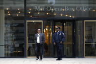 Two Lincoln Center security officials walk in front of the Metropolitan Opera box office Thursday, March 12, 2020, in New York after New York Gov. Andrew Cuomo temporarily banned gatherings of more than 500 people. Most of Lincoln Center's performance space,s including the Met Opera, shuttered their doors Thursday after the ban was announced. (AP Photo/Kathy Willens)