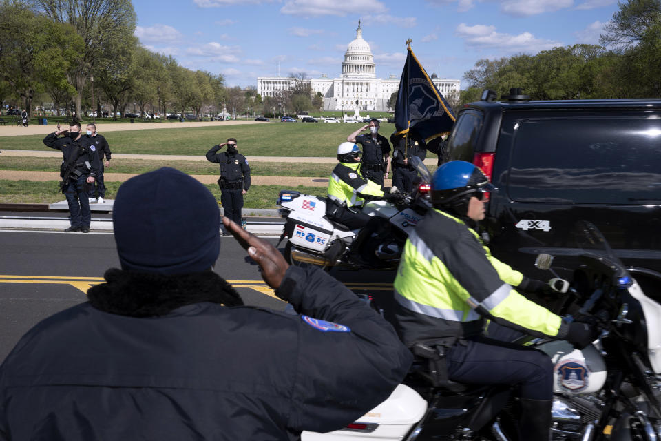 With the U.S. Capitol in the background, U.S. Capitol Police officers salute as procession carries the remains of a U.S. Capitol Police officer who was killed after a man rammed a car into two officers at a barricade outside the Capitol in Washington, Friday, April 2, 2021. (AP Photo/Jose Luis Magana)