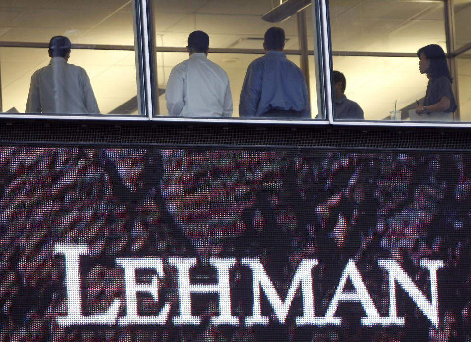 People stand next to windows above an exterior sign at the Lehman Brothers headquarters in New York in this September 16, 2008 file photo. September 14, 2009 marks the one year anniversary of the bankruptcy filing of Lehman Brothers. Picture taken September 16, 2008.  REUTERS/Chip East/Files  (UNITED STATES BUSINESS EMPLOYMENT ANNIVERSARY)