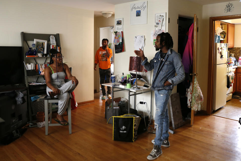 Keyon Robinson, center rear, talks on the phone to a manager at the restaurant where he works, while his older sister, Sierra Bryant, converses with family friend Leon Watson, on Monday, Aug. 15, 2022, in Oak Park, Ill. (AP Photo/Martha Irvine)