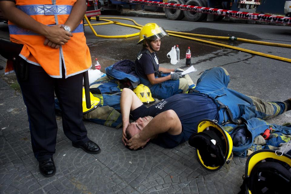 Algunos bomberos toman un descanso en su labor de extinción de un incendio en la empresa Iron Mountain en que se habían registrado nueve muertos, incluso bomberos, en Buenos Aires, Argentina, el miércoles 5 de febrero de 2014. (AP Photo/Rodrigo Abd)