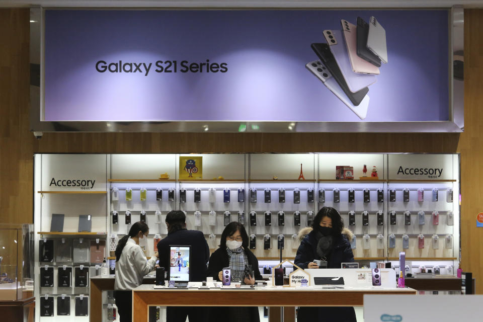 Visitors try out Samsung Electronics' Galaxy Z Folder2 5G smartphones at its shop in Seoul, South Korea, Thursday, Jan. 28, 2021. Samsung Electronics Co. said Thursday its operating profit for last quarter rose by more than 26% as it capped off a robust business year where its dual strength in parts and finished products allowed it to thrive amid the pandemic. (AP Photo/Ahn Young-joon)