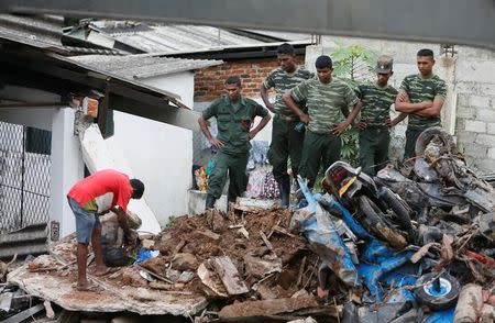 A man opens a bag next to military officers during a rescue mission after a garbage dump collapsed and buried dozens of houses in Colombo, Sri Lanka April 15, 2017. REUTERS/Dinuka Liyanawatte