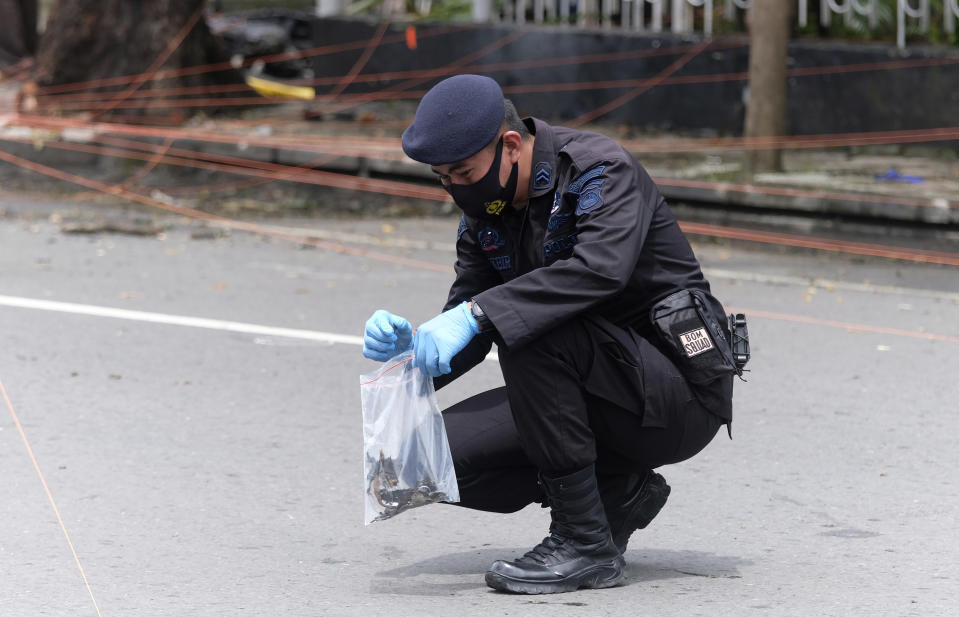 A member of the police bomb squad collects evidence from around the site of a bomb attack at the Sacred Heart of Jesus Cathedral in Makassar, South Sulawesi, Indonesia, Monday, March 29, 2021. Two attackers believed to be members of a militant network that pledged allegiance to the Islamic State group blew themselves up outside the packed Roman Catholic cathedral during a Palm Sunday Mass on Indonesia's Sulawesi island, wounding a number of people, police said. (AP Photo/Masyudi S. Firmansyah)