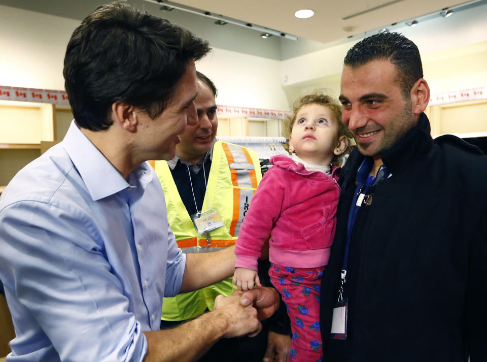 Syrian refugees are greeted by Canada's Prime Minister Justin Trudeau (L) on their arrival from Beirut at the Toronto Pearson International Airport in Mississauga, Ontario, Canada December 11, 2015. After months of promises and weeks of preparation, the first Canadian government planeload of Syrian refugees landed in Toronto on Thursday, aboard a military aircraft met by Prime Minister Justin Trudeau.  REUTERS/Mark Blinch 