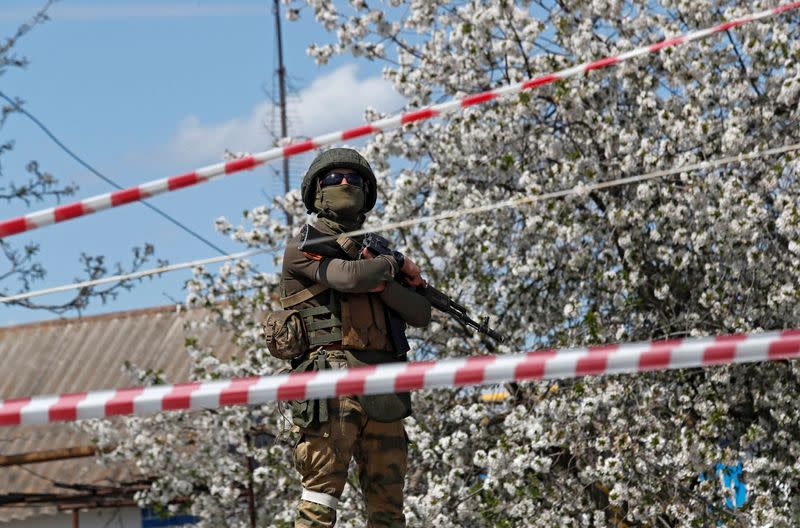 A service member of pro-Russian troops stands guard near a temporary accommodation centre in Bezimenne