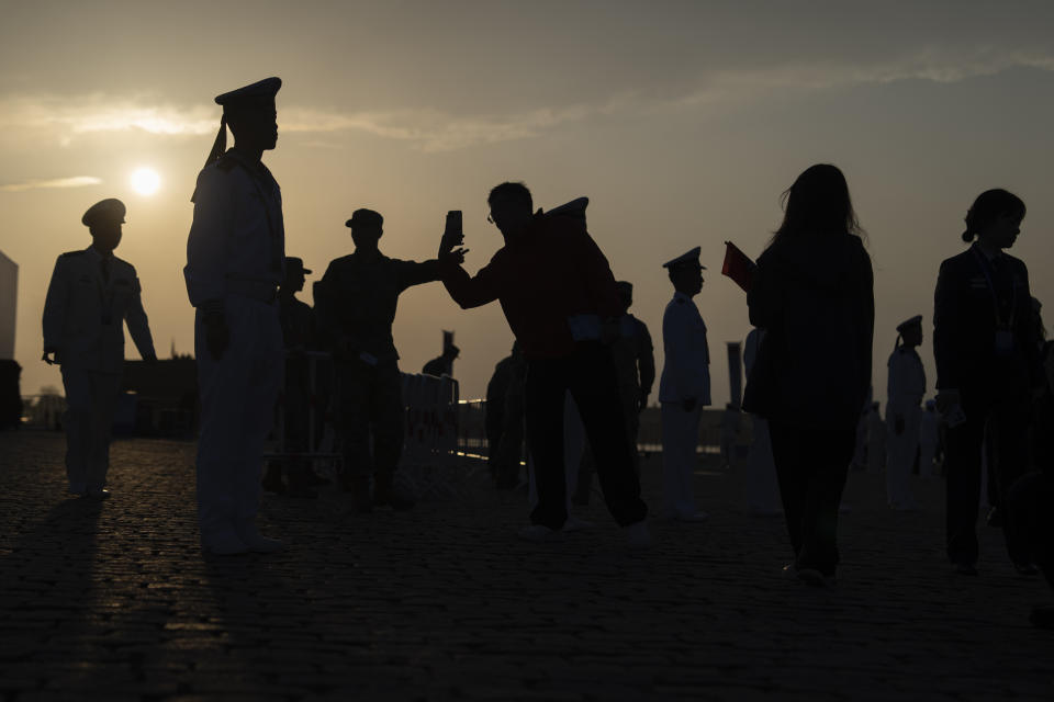 Chinese sailors are silhouetted with attendees leaving after visiting Chinese warships during a public day to mark the 75th anniversary of Chinese People's Liberation Army Navy in Qingdao in eastern China's Shandong province on Tuesday, April 23, 2024. (AP Photo/Ng Han Guan)