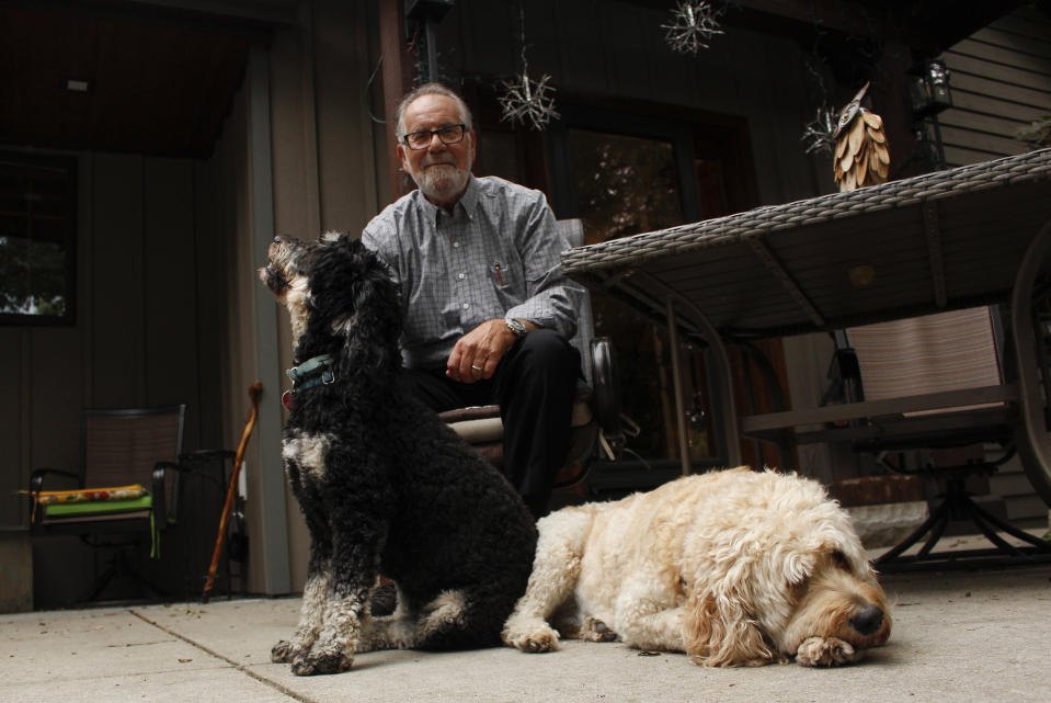 Gordon Haberman sits for a photo with his two dogs, Tuesday, Sept. 6, 2022 in West Bend, Wis. His daughter Andrea Haberman died in the Sept. 11, 2001 attacks in New York. The self-professed architect of that day's destruction, Khalid Sheik Mohammed, was captured in 2003 and still has not stood trial. Several who spoke to The Associated Press, including Haberman, have not given up hope that he might still be held accountable. (AP Photo/Carrie Antlfinger)