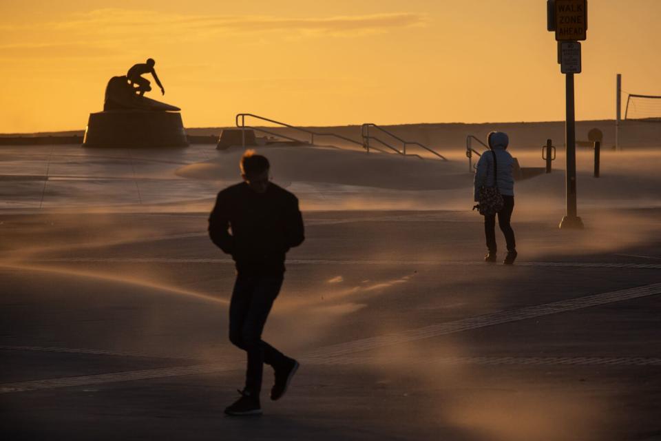 High winds blow sand inland pelting walkers and forming piles along Pier Plaza in Hermosa Beach.