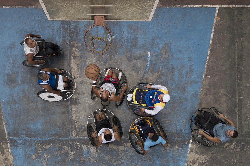 Manuel Mendoza juega baloncesto con sus amigos en silla de ruedas en una cancha pública en el barrio Artigas de Caracas, Venezuela, sábado 24 de octubre de 2020. (AP Foto/Matias Delacroix)