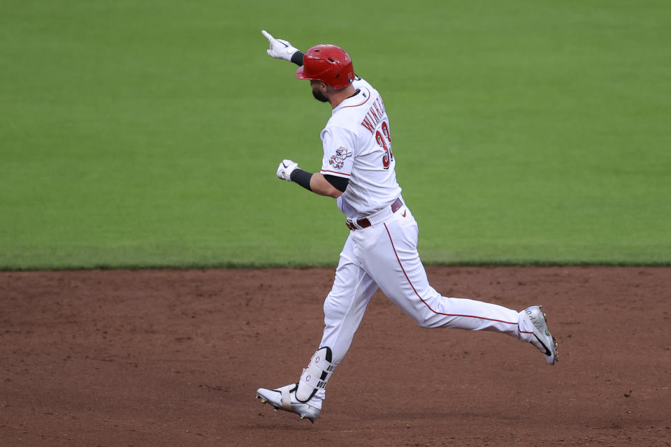 Cincinnati Reds' Jesse Winker points to fans in the outfield as he runs the bases after hitting a solo home run during the third inning of a baseball game against the Milwaukee Brewers in Cincinnati, Friday, May 21, 2021. (AP Photo/Aaron Doster)