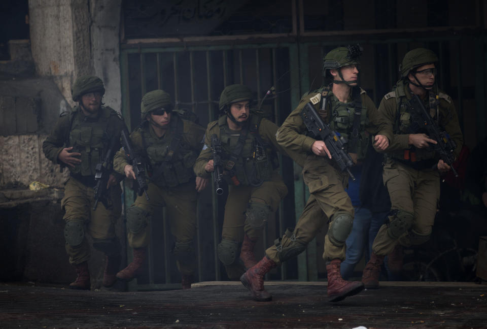 Israeli troops take their position during clashes with Palestinian demonstrators in the West Bank city of Hebron, Monday, Dec. 9, 2019. Palestinian residents held a general strike to protest an Israeli plan to build a new Jewish neighborhood in the heart of the West Bank's largest city. (AP Photo/Majdi Mohammed)