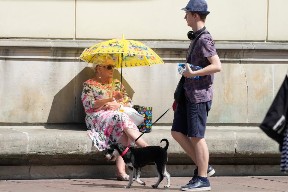 A woman protects herself from sunshine with an umbrella during a hot day in downtown Warsaw (AP)