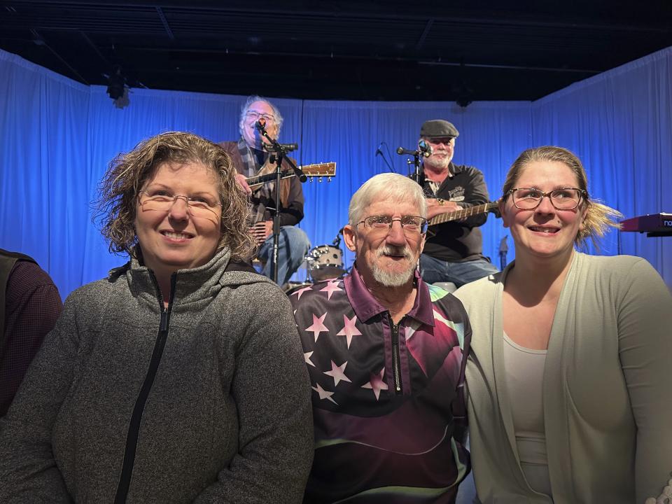 From left, Kathy Lebel, Tom Giberti and Samantha Juray, attend a benefit concert in Lewiston, Maine on Jan. 6, 2024. Immediately after Maine's deadliest mass shooting, the owners of the bowling alley and the bar in Lewiston where the gunman killed a total of 18 people were certain their doors were closed for good. Yet as time passed, they came to the same conclusion: They had to reopen. (AP Photo/Nick Perry)