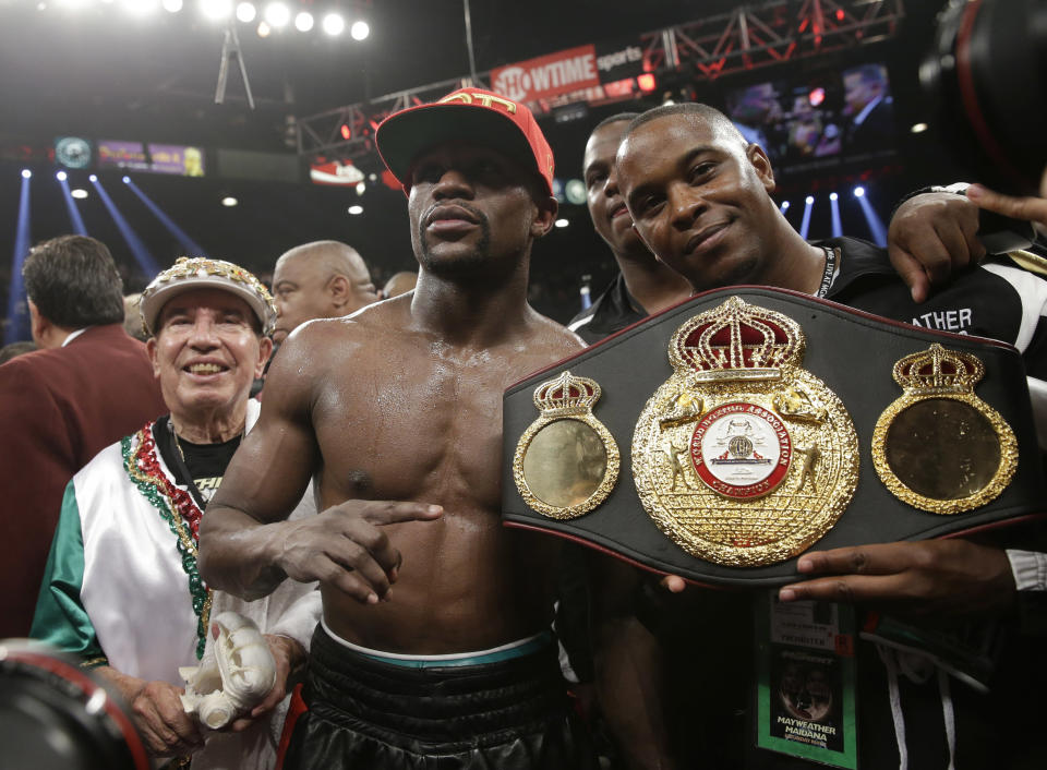 Floyd Mayweather Jr., center, poses with his corner and a champion's belt after his WBC-WBA welterweight title boxing fight against Marcos Maidana Saturday, May 3, 2014, in Las Vegas. Mayweather won the bout by majority decision. (AP Photo/Isaac Brekken)