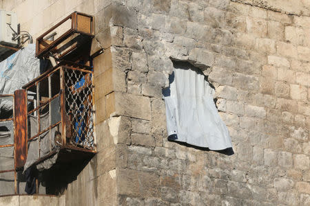 A curtain hangs out a hole in the wall in a damaged building in rebel-held besieged old Aleppo, Syria December 2, 2016. REUTERS/Abdalrhman Ismail