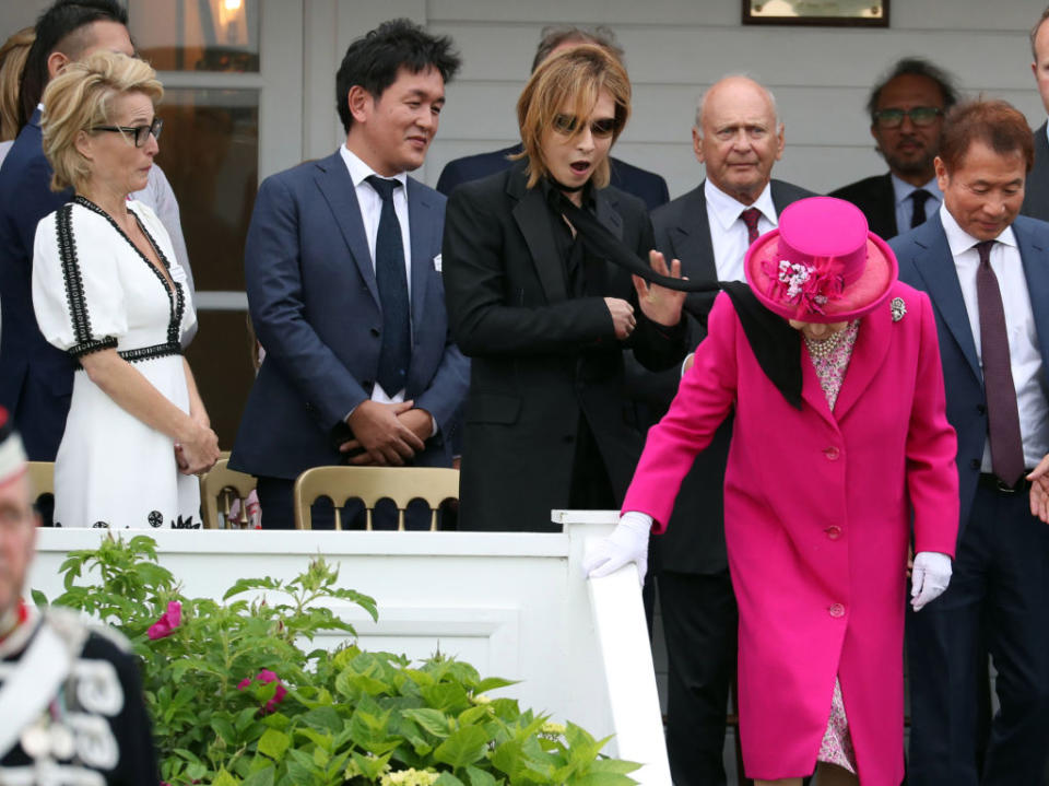 Gillian Anderson (left) watches as a scarf blows into Queen Elizabeth II during the OUT-SOURCING Inc Royal Windsor Cup at the Guards Polo Club, Windsor Great Park, Egham, Surrey.