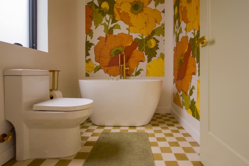 Bathroom with graphic floral wallpaper and checkerboard flooring.