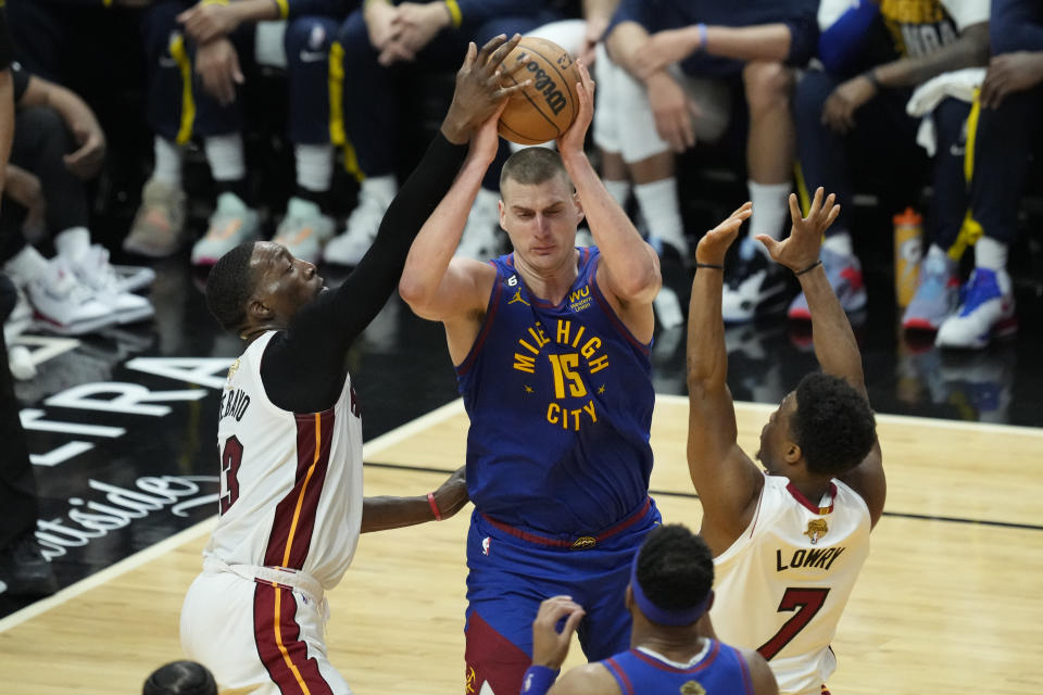 Miami Heat guard Kyle Lowry (7) and center Bam Adebayo (13) defend Denver Nuggets center Nikola Jokic (15) during the first half of Game 3 of the NBA Finals basketball game, Wednesday, June 7, 2023, in Miami. (AP Photo/Rebecca Blackwell)