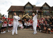 In this handout image provided by LOCOG, Torchbearer 109 Peter Wyatt passes the Olympic Flame to Torchbearer 110 Camilla Hadland outside Shakespeare's Birthplace in Stratford-Upon-Avon during day 44 of the Olympic Flame Torch Relay on July 1, 2012 in Stratford-upon-Avon, England. The Olympic Flame is now on day 44 of a 70-day relay involving 8,000 torchbearers covering 8,000 miles. (Photo by LOCOG via Getty Images)