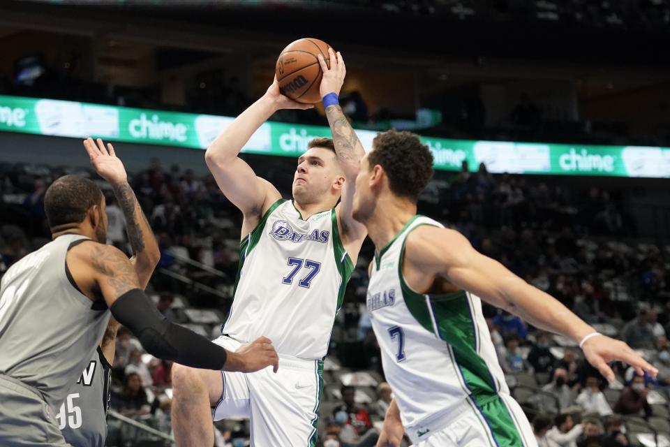 Dallas Mavericks guard Luka Doncic (77) takes a shot as Brooklyn Nets' LaMarcus Aldridge, left, and Dwight Powell (7) look on in the first half of an NBA basketball game in Dallas, Tuesday, Dec. 7, 2021. (AP Photo/Tony Gutierrez)